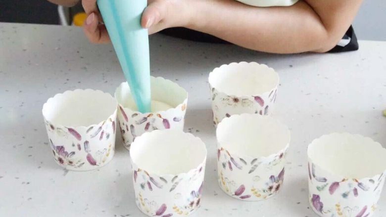人人都可以做的戚风纸杯蛋糕,将搅匀的蛋糕浆液装入裱花袋中，一次挤进每个纸杯中。