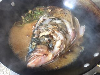 红烧鱼头粉皮,两边都煎到金黄色了，转移到大炒锅里去。加入黄酒、生抽、老抽、蚝油、冰糖，倒水。开大火煮。