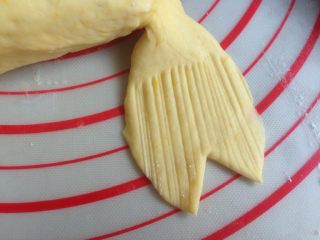 香肠锦鲤包,用刮板压出若干条细纹，再切出三角，尾鳍基本成形