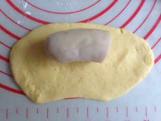 香肠锦鲤包,擀成长度13CM左右的椭圆形，其中一条长边向下擀薄一点，放上半根香肠