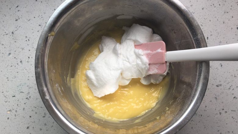 酸奶小蛋糕,加一半蛋白霜到蛋黄糊中，翻拌均匀