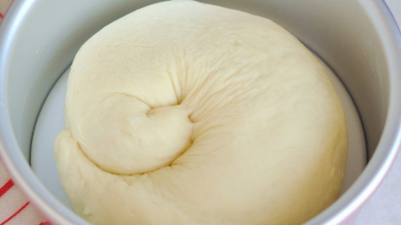 苹果肉桂面包,轻轻将面团卷起，盘在六寸蛋糕圆模中，放入烤箱发酵40分钟左右，同时烤箱内部要放一碗开水。
