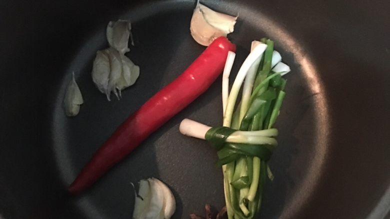 电饭锅卤猪脚,锅内先放入洗过且略拍过的蒜头、辣椒、葱还有八角。