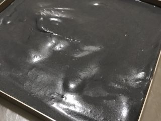 黑·竹炭咸奥利奥蛋糕卷,用刮刀轻轻抹平，用手轻拍烤盘底部，震破大气泡