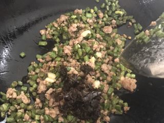 干煸橄榄肉沫豆角,再加入橄榄菜，尽量沥干油，等到橄榄菜炒香，加少许白糖
