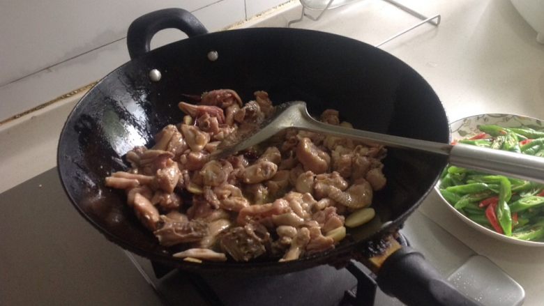 双椒小炒鸡,倒入腌好的鸡块，中火煸炒至鸡脱水并呈金黄色（中间再加约一勺盐和半勺糖）。