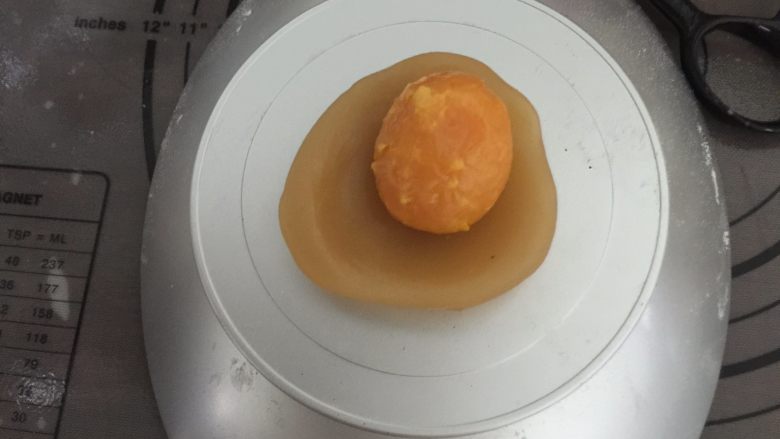 蛋黄莲蓉月饼,取一个莲蓉圆球压扁，中间放上一颗烤过的咸蛋黄