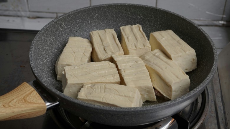 煎酿豆腐,转中火，将豆腐有馅的一面朝下，一块块放在锅里。