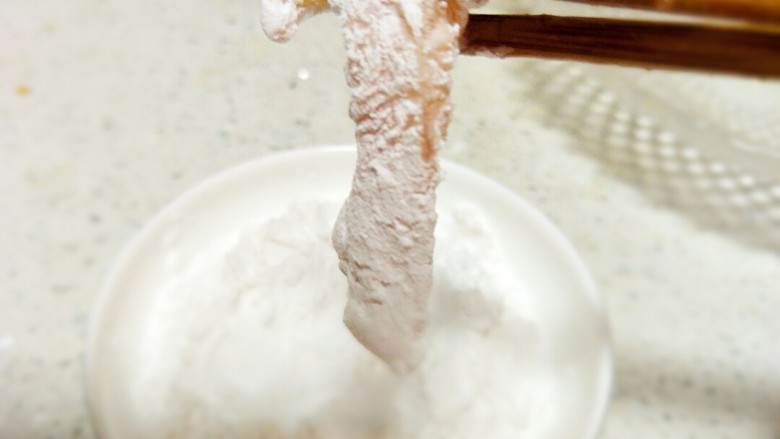 （鸡胸版）糖醋里脊,夹起裹匀蛋清的鸡胸肉在生粉里沾一下，均匀的沾上生粉。