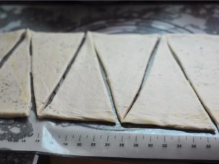 黑白芝麻可颂,将冷藏后的面团擀至4厘米厚，切割成底边为10厘米、高为25厘米的等腰三角形