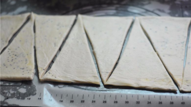 黑白芝麻可颂,将冷藏后的面团擀至4厘米厚，切割成底边为10厘米、高为25厘米的等腰三角形