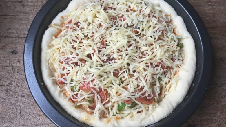 双酱培根披萨,按照一层菜一层芝士的顺序放入培根、洋葱丝、青椒丝，最上面再撒适量芝士；
