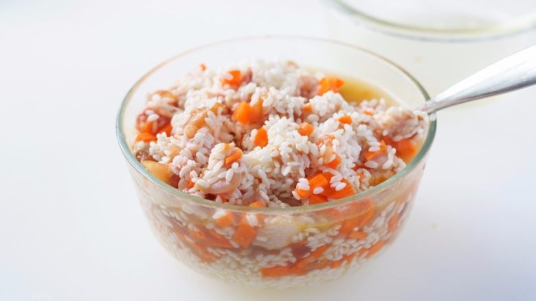 竹筒鸡肉米饭,挑出生姜，把腌渍好的鸡肉胡萝卜丁倒入盛有大米的容器里拌匀。