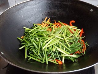 炒三丝,热锅下油，加入胡萝卜丝，红椒丝和韭菜芯。
