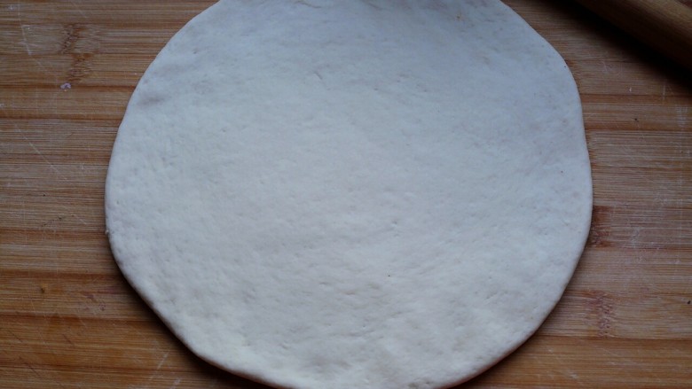 海鲜披萨,醒发好的面团擀成比九寸圆模底稍大一点的圆片。