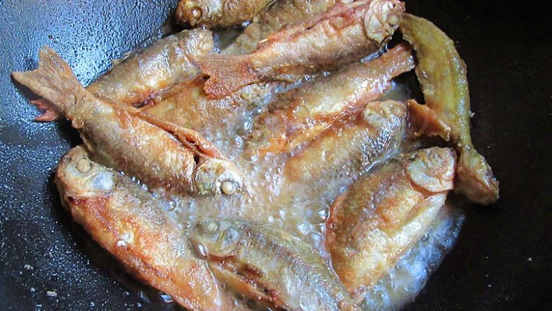 家乡特色美食——杂鱼炖小豆饼,热锅注入油烧至7成热，将过拿起摇晃一下，放入小鱼慢火煎