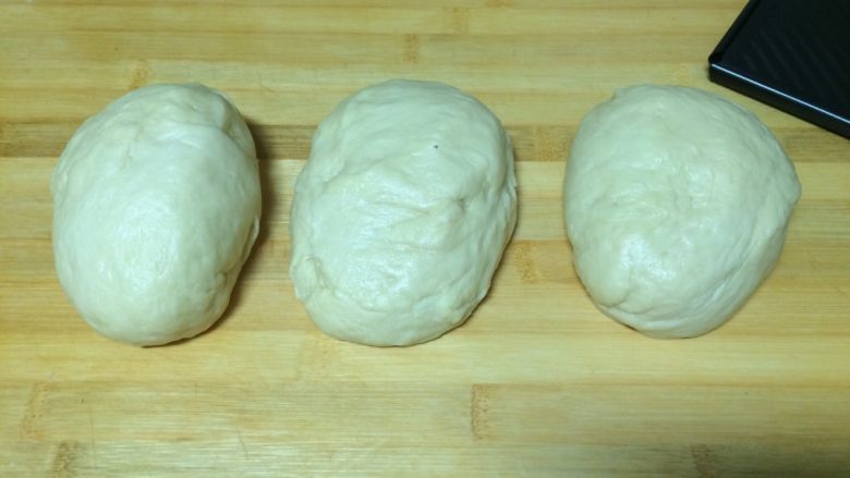 蜂蜜小面包,发酵好的面团，直接在面包机中启动揉面程序，面团排气8分钟，取出后分出一半面团做小面包，另一半做吐司，先把这一半面团分成三个大剂子
