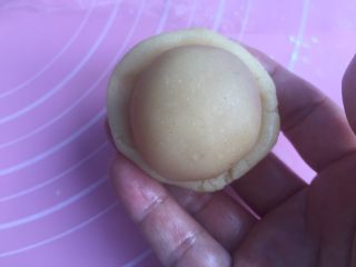 莲蓉蛋黄月饼（50克）,手上沾点油防粘。把饼皮捏成弧形底的小圆皮。放入馅料。