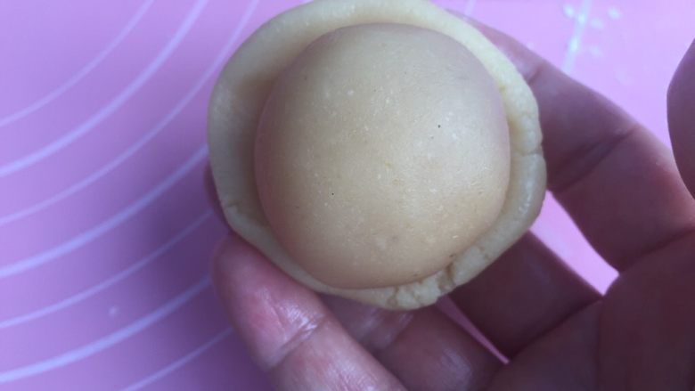 莲蓉蛋黄月饼（50克）,手上沾点油防粘。把饼皮捏成弧形底的小圆皮。放入馅料。