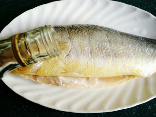 清蒸黄鱼,倒入一点料酒，用手涂抹在鱼上。