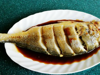 清蒸黄鱼,把鱼上的姜片去掉，往盘里倒入适量的蒸鱼豉油。