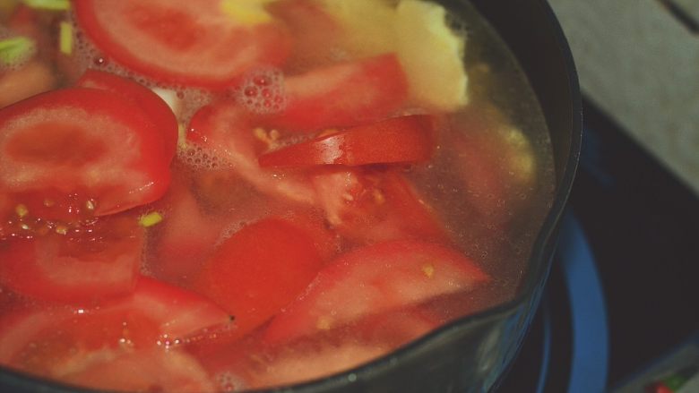番茄鸡蛋汤,锅中倒入开水。番茄，葱白与蒜瓣放入。