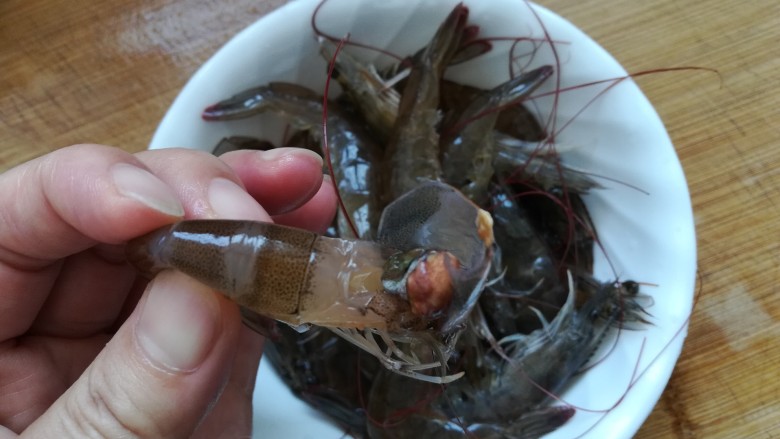 土豆虾球,现在开始处理虾，把虾头部打开，去除头部，取出虾肠（虾肠在虾的背部至尾巴处那条黑线）。