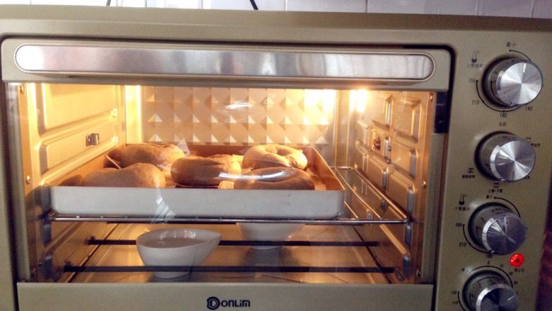黑芝麻贝果,东菱烤箱内放置一碗热开水，温度调到30度，将面包胚放入烤箱内发酵30分钟