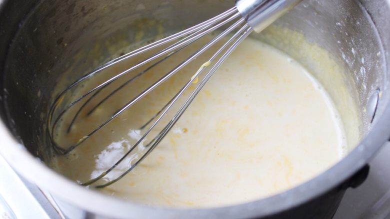 #不一样的泡芙#樱花卡仕达酱萝莉泡芙,牛奶大概倒入三分之一入打发好的淀粉蛋黄糊内。使之混合均匀。