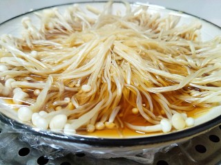 最好吃的油泼金针菇,把浇好汁的金针菇覆盖上食品级保鲜膜。放进锅里蒸，上气后蒸10分钟。
