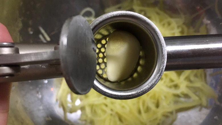 炝拌土豆丝,捞出沥干水分放深容器中，在上面夹两瓣蒜蓉
