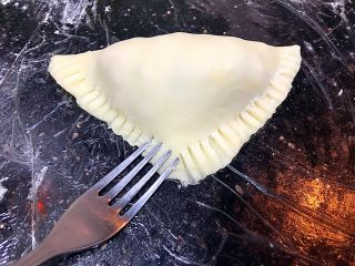中式三角叉烧酥,用小叉子按压三角面团切口，使面团更严实，在烤制时不会裂开。

