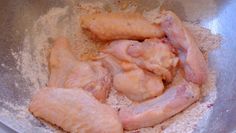 怎样把鸡翅吃干抹净(煎烤蒸三法）,从冰箱中取出腌制好的鸡翅 放进面粉堆里翻滚 让鸡翅表面都沾上料粉