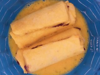 紫薯香蕉吐司卷,鸡蛋打散 吐司卷放入蛋液中浸泡