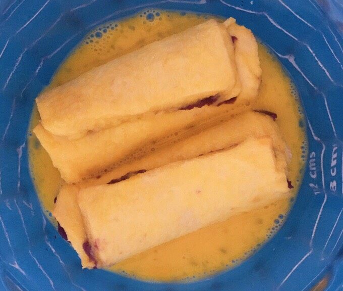 紫薯香蕉吐司卷,鸡蛋打散 吐司卷放入蛋液中浸泡