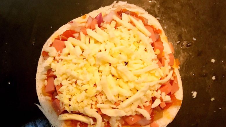 剩馒头的春天  馒头火腿披萨,最后再撒上一层芝士碎即可，逐一做好另外2片馒头，把做好的披萨坯放入烤盘