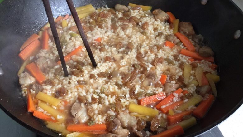 新疆碎肉抓饭,大约20分钟，水分快干时，筷子插入锅里，使抓饭的热气上升，水分下沉；