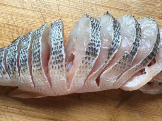 清蒸鲈鱼,再从鱼背部开始切成薄片，鱼肚那部分鱼肉相连，不要切断了，一直切到鱼尾。