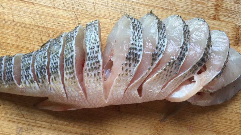 清蒸鲈鱼,再从鱼背部开始切成薄片，鱼肚那部分鱼肉相连，不要切断了，一直切到鱼尾。