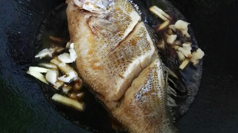 红烧鲈鱼,加入姜蒜。