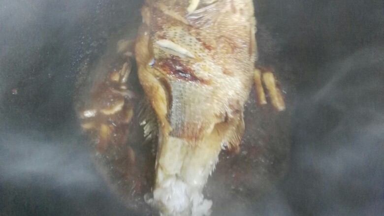 红烧鲈鱼,把鱼翻面让鱼全身都沾上调料。