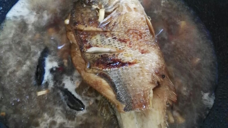 红烧鲈鱼,水开后盖上锅盖中大火煮。