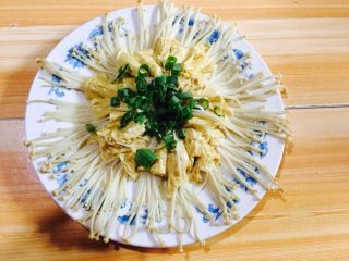 蒜香豆皮金针菇,将蒸好的豆皮金针菇盘子里的水控干，将少许葱叶碎放在中间