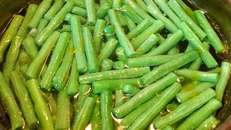 绿色美食+健康少油蒜泥拌长豆（豇豆）,将长豆倒入锅内，不要盖盖子，用筷子将长豆搅动几下，使其受热均匀