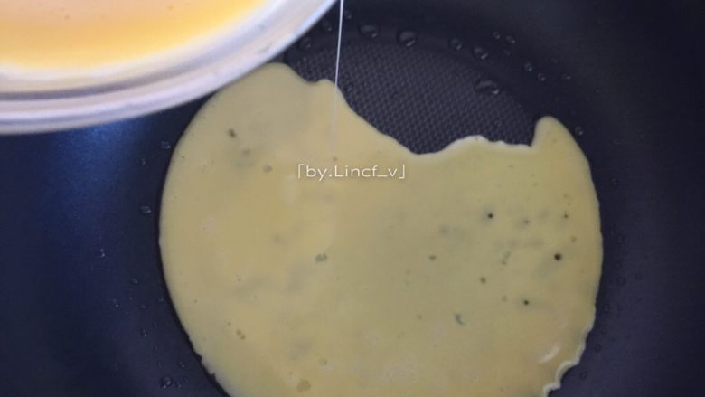寿司玉子烧,倒入1/3的牛奶蛋液，转动煎锅使蛋液均匀平铺煎锅，煎至未完全凝固时卷起