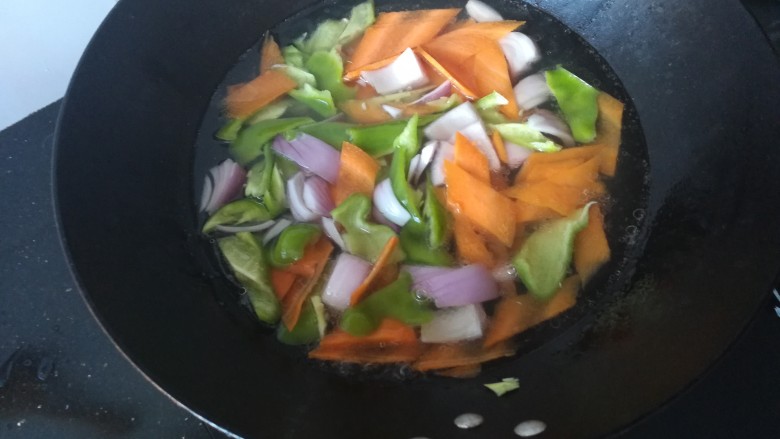 麦穗鱿鱼花,锅里水烧开，加入适量油和盐，把切好的洋葱、胡萝卜、青椒入开水锅焯一分钟。