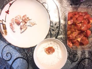 菠萝咕咾肉,二十分钟后，肉取出；取一空碗倒入淀粉，将腌好的肉块裹上一层生粉备用；