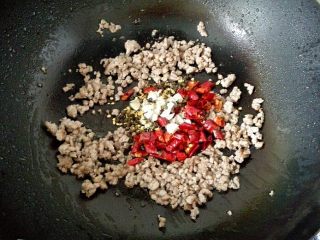 干煸豆角,5．	将蒜末和干辣椒放入锅中，煸炒至干辣椒变红亮出香味。