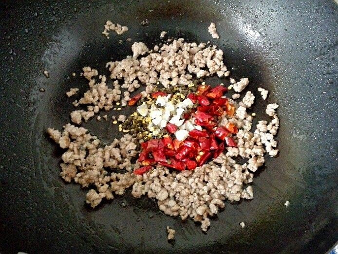 干煸豆角,5．	将蒜末和干辣椒放入锅中，煸炒至干辣椒变红亮出香味。