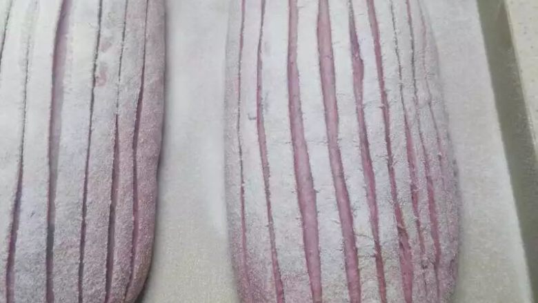 紫薯版麻薯软欧,筛上面粉，用刀片割出条纹。